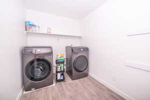 Laundry room with light wood-style flooring and independent washer and dryer