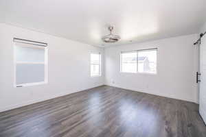 Unfurnished room featuring a barn door and dark wood-style floors