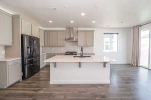 Kitchen featuring gray cabinetry, stainless steel appliances, a center island with sink, a breakfast bar, and recessed lighting