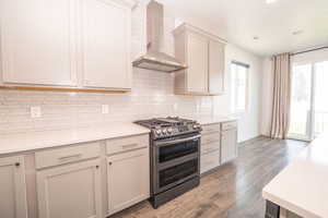 Kitchen with double oven range, dark wood-style floors, light stone counters, tasteful backsplash, and recessed lighting