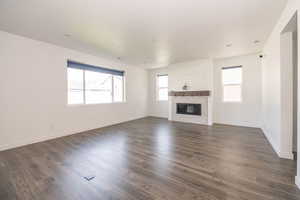 Unfurnished living room with a glass covered fireplace and dark wood finished floors