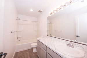 Bathroom with vanity, dark wood finished floors, and shower / washtub combination