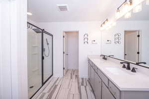 Full bathroom featuring a shower stall and double vanity