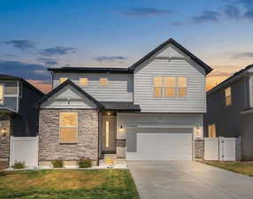 View of front of house with stone siding, a gate, concrete driveway, and an attached garage