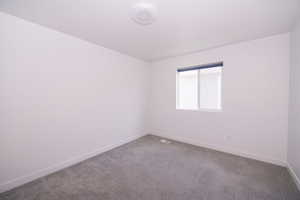 Carpeted spare room featuring baseboards