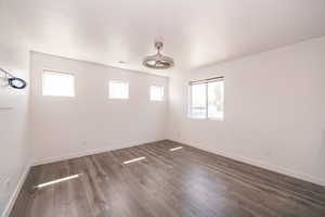 Unfurnished room with dark wood-style flooring, plenty of natural light, and a ceiling fan