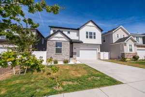View of front of house with an attached garage, concrete driveway, and stone siding