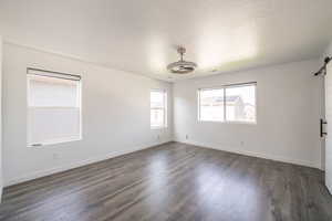 Empty room featuring a barn door, dark wood-style flooring, and a textured ceiling