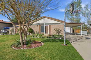 View of front facade featuring brick siding, a carport, and driveway