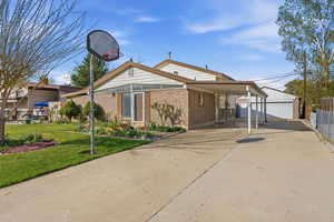 Back of property with an outbuilding, an attached carport, brick siding, and concrete driveway
