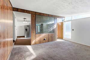 Carpeted empty room featuring wood walls and a textured ceiling