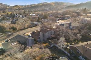 Aerial view of property and surrounding area featuring nearby suburban area and a mountain backdrop