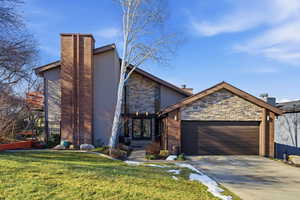 View of front of home featuring stone siding, french doors, a garage, and a chimney
