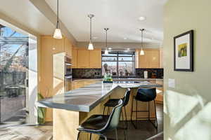 Kitchen featuring light wood finish cabinetry, decorative light fixtures, and a kitchen island