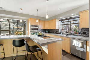 Kitchen with light wood finish cabinets, stainless steel appliances, and tasteful backsplash