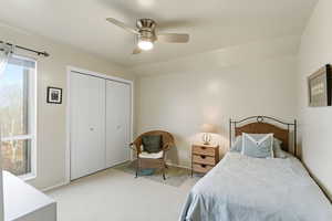 Bedroom featuring a closet, light carpet, ceiling fan, and vaulted ceiling