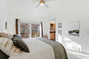 Carpeted bedroom with ceiling fan, vaulted ceiling, and ensuite bath