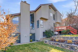 Rear view of house with a yard, stucco siding, a chimney, and a deck