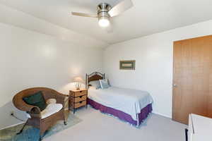 Bedroom with vaulted ceiling, a ceiling fan, and light colored carpet