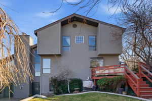 Rear view of house featuring stucco siding, a wooden deck, and a yard