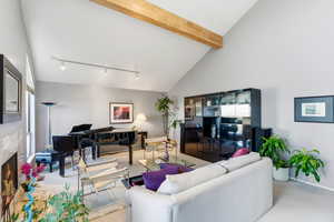 Living area with a high end fireplace, vaulted ceiling, carpet, and rail lighting