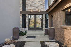 Property entrance with french doors, brick siding, and stone siding