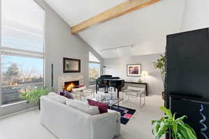 Living area featuring light colored carpet, a fireplace, and lofted ceiling