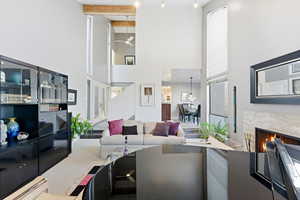 Living room featuring a high end fireplace, a high ceiling, a ceiling fan, and carpet floors