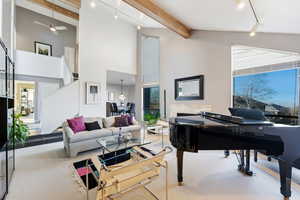 Living room featuring rail lighting, ceiling fan, and light carpet