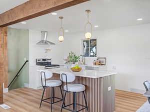Kitchen featuring a kitchen island, stainless steel range with electric cooktop, a kitchen breakfast bar, and light wood-style floors