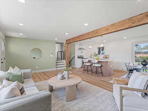 Living room featuring light wood-style flooring, beam ceiling, and recessed lighting