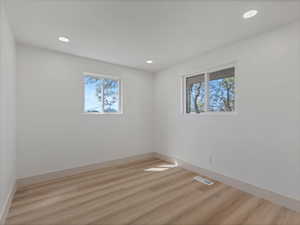 Unfurnished room with light wood-style flooring, healthy amount of natural light, and recessed lighting