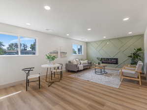 Living room featuring an accent wall, recessed lighting, and light wood-style flooring