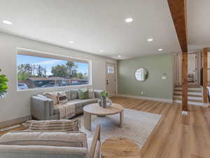 Living room with a textured ceiling, light wood-style flooring, and recessed lighting
