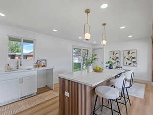 Kitchen featuring light wood-style flooring, a breakfast bar, light stone countertops, and a kitchen island