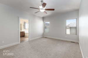Unfurnished primary suitevfeaturing light carpet, ensuite bath, and ceiling fan
