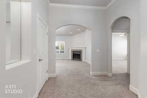 Home entry, featuring light carpet, arched walkways, ornamental molding, and recessed lighting