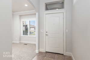 Entrance foyer featuring light carpet, recessed lighting, crown molding, arched walkways, and light tile patterned floors