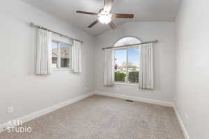 Carpeted empty room featuring lofted ceiling and a ceiling fan