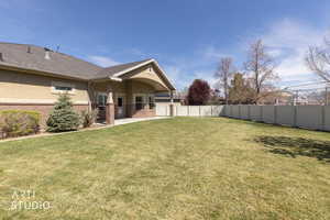 Fenced backyard with covered patio, back lawn, and fenced yard