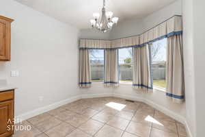 Unfurnished dining area featuring vaulted ceiling, hanging lights, and light tile patterned floors