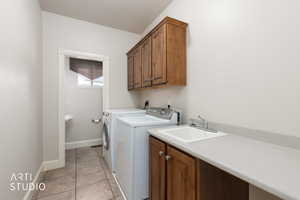 Laundry area featuring light tile patterned floors, separate washer and dryer, and cabinet space