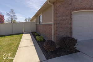 View of side of property with brick, side gate, and a garage