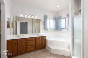 Primary Bathroom with double vanity, a shower stall, a bath, and light tile patterned floors