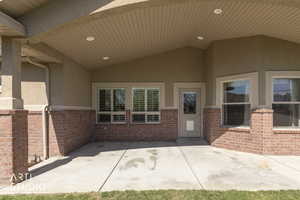 Property rear entrance featuring stucco siding, a patio area, and brick siding