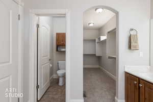 Primary Bathroom featuring vanity, light carpet, a spacious walk-in closet, and light tile patterned floors