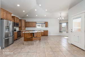 Kitchen with lofted ceiling, light countertops, stainless steel appliances, wood finish cabinets, and a breakfast bar