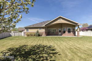 Rear view of house featuring a fenced backyard, brick siding, covered patio area, and stucco siding