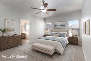 Primary Suite featuring light colored carpet, a ceiling fan, and ensuite bath (Virtually Staged)