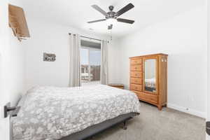 Carpeted bedroom with ceiling fan and baseboards